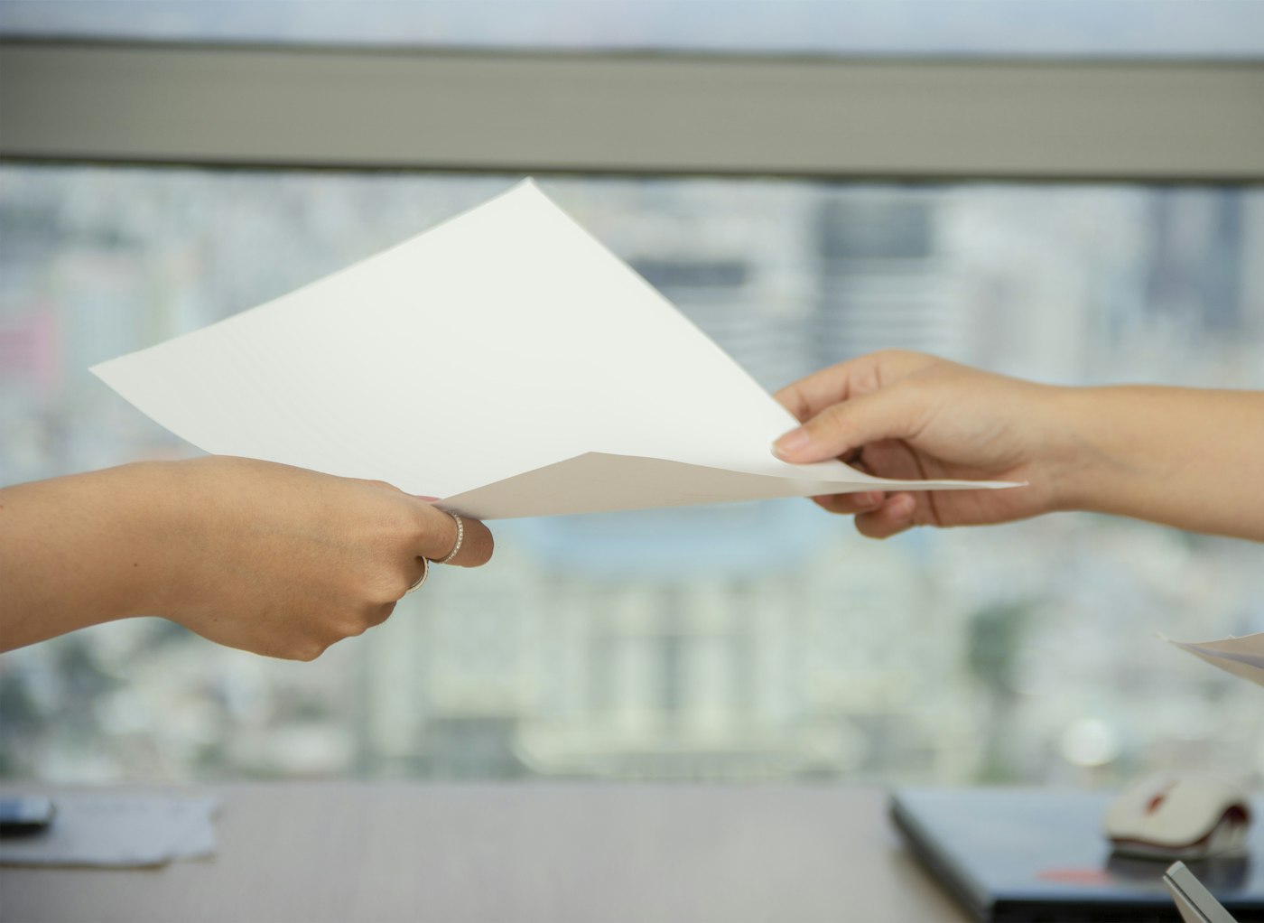 Mãos trocando um documento entre duas pessoas, representando a emissão da certidão negativa do MEI