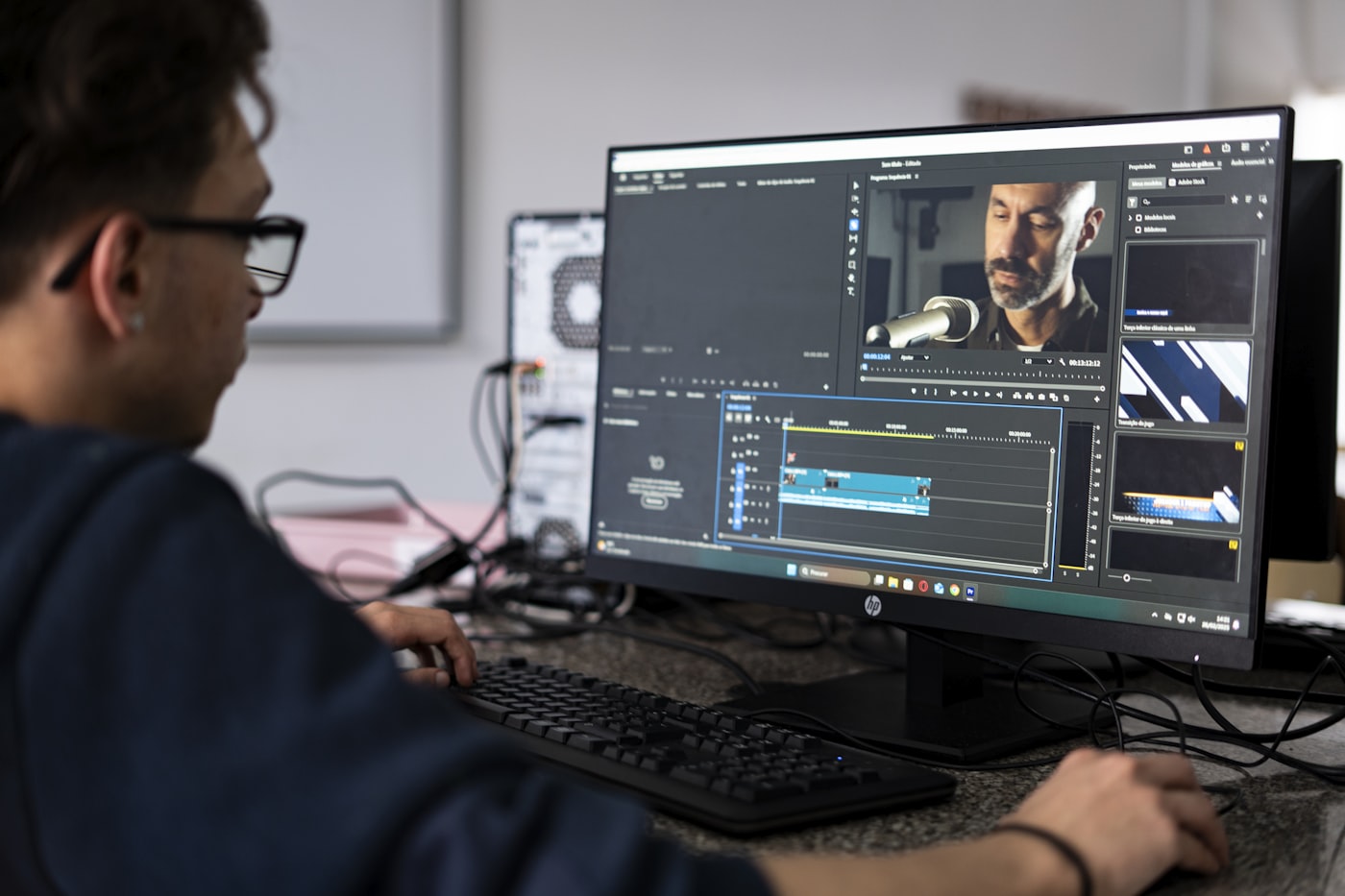 Editor de vídeo trabalhando na timeline de edição em dois monitores, representando o editor de vídeo formalizado como MEI