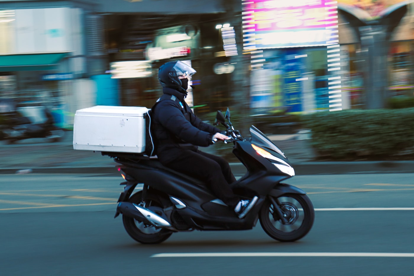 Entregador em scooter com baú de entrega na garupa, representando o entregador de aplicativo formalizado como MEI