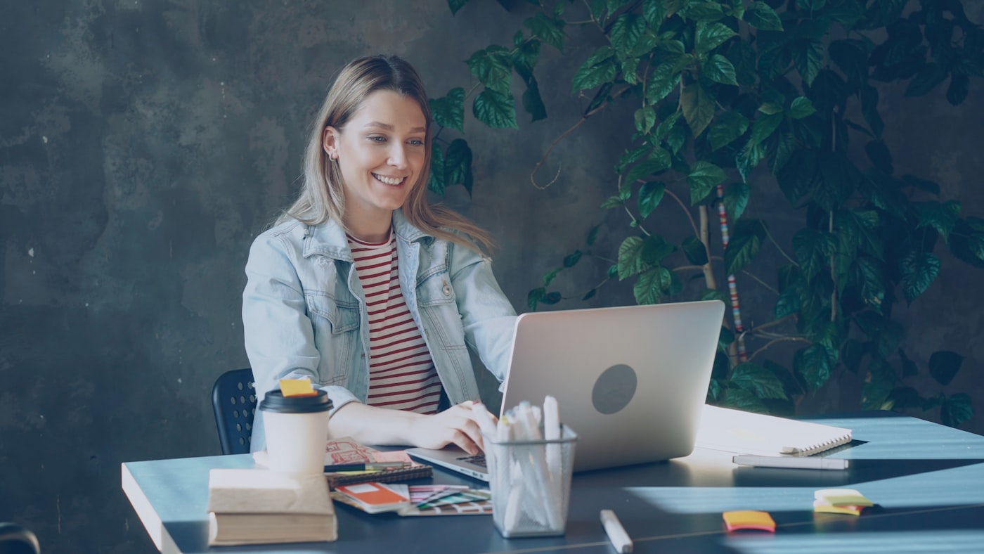 Empreendedora MEI sorrindo enquanto trabalha no notebook