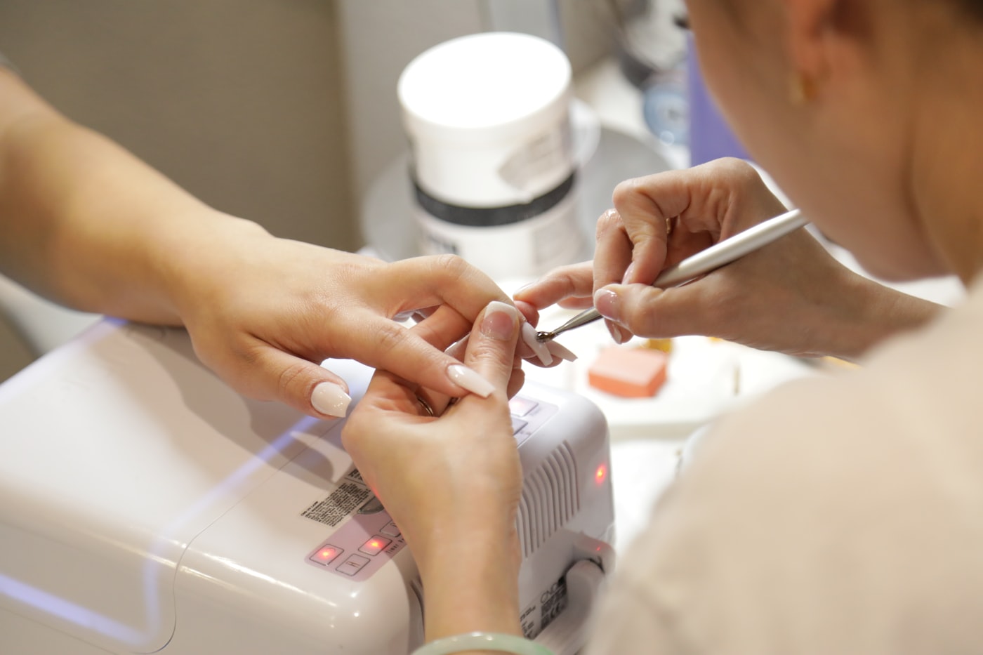 Manicure fazendo as unhas de uma cliente no salão, representando a manicure formalizada como MEI
