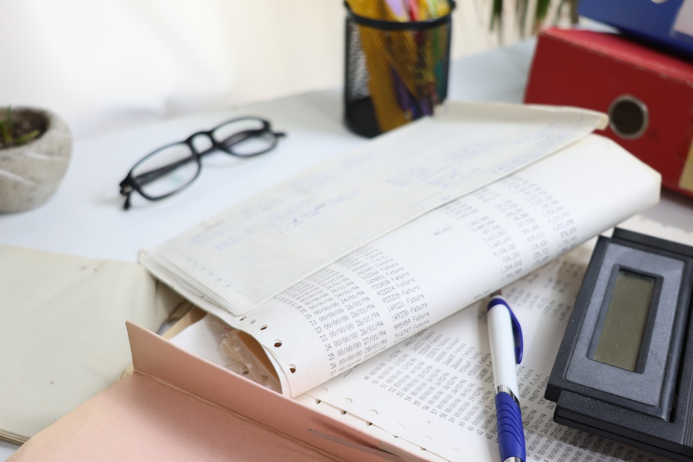 Mesa de trabalho com documentos, calculadora e óculos, representando o controle mensal do DAS