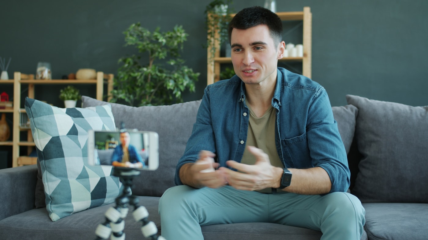 Homem gravando conteúdo com celular em tripé na sala, representando o social media formalizado como MEI